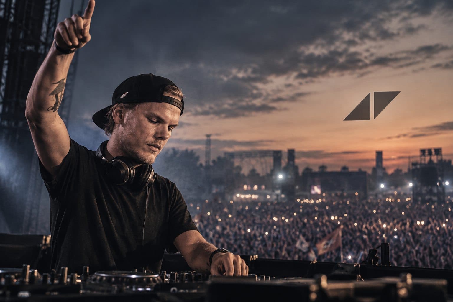 Avicii performing at dusk before festival lights and a large crowd