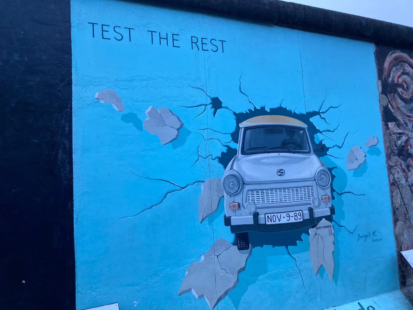 Un Trabant pintado parece atravesar una pared azul en el mural de Birgit Kinder.