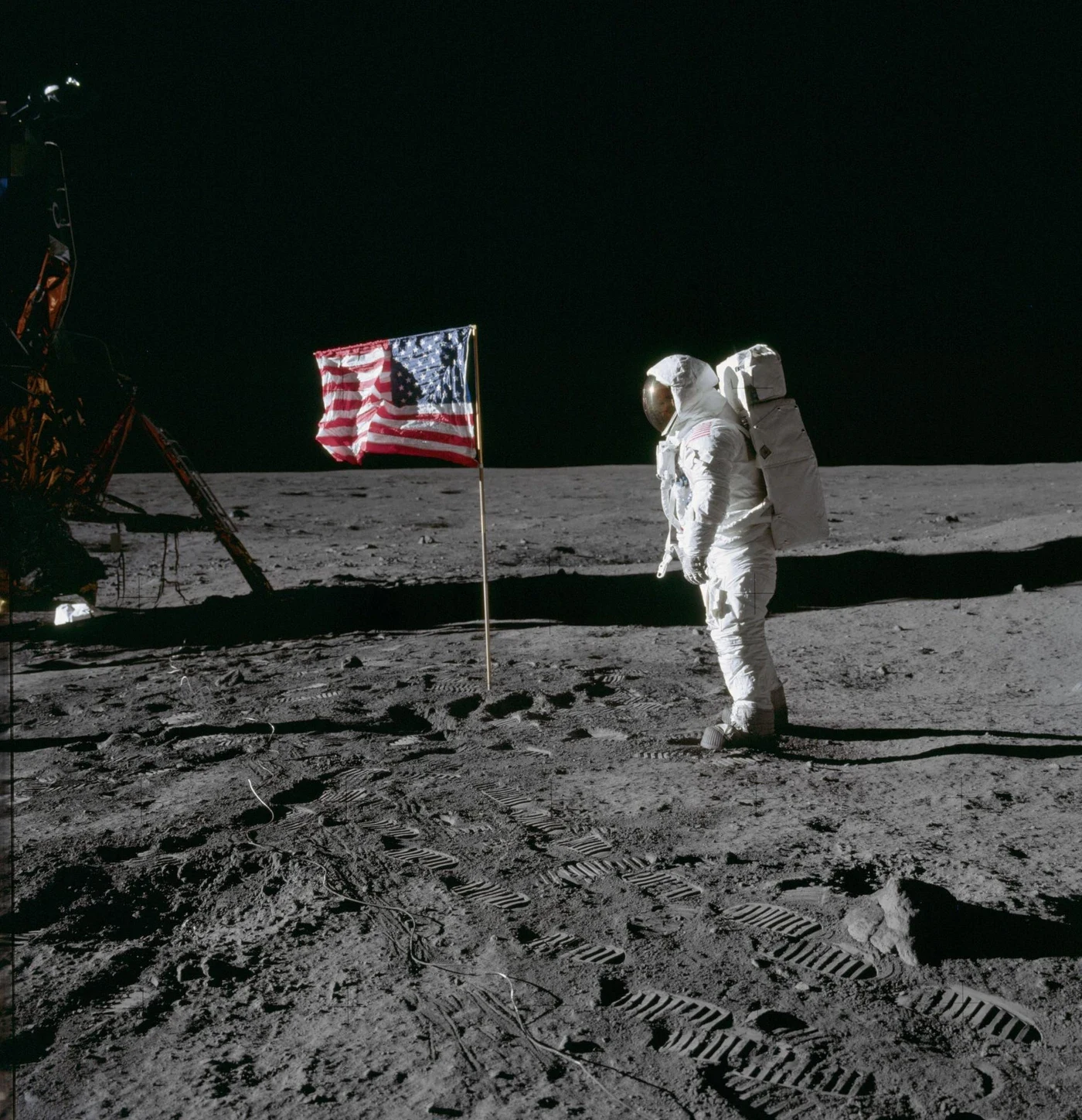 Buzz Aldrin stands beside the supported American flag on the lunar surface.