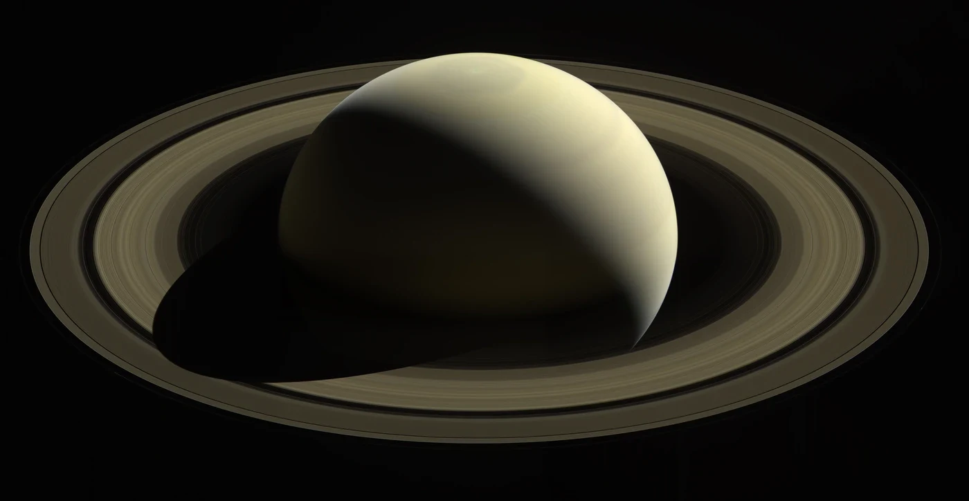 Globe pâle de Saturne entouré de ses larges anneaux