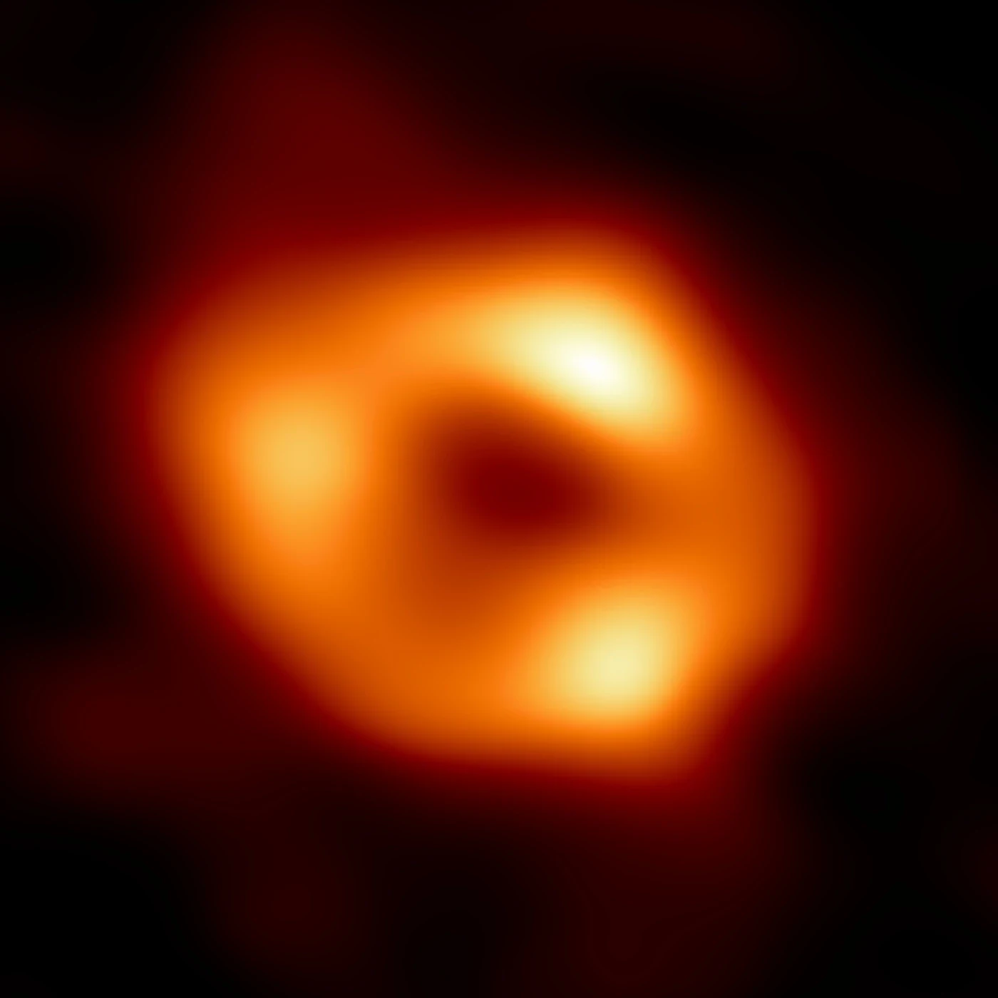 An orange ring of reconstructed radio emission surrounds the dark shadow of Sagittarius A*.