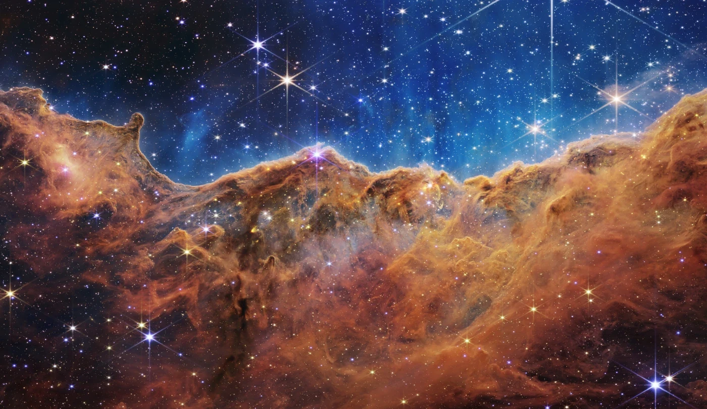 Glowing gas and dark dust form a jagged ridge beneath numerous stars in Webb’s infrared view of NGC 3324.